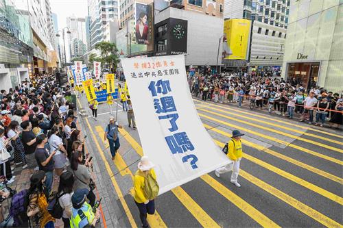 '圖11：法輪功學員舉起大型幡旗，呼籲大陸民眾退出中共黨團隊。'