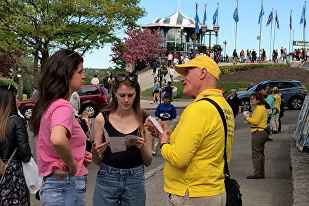 '圖18：參加當天活動的魁北克市法輪功學員Alain（圖右）一直在廣場上和人們交談，傳遞法輪大法真相。'