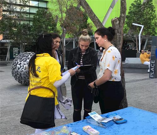 '圖6：澳洲西人女孩子奧利維亞（Olivia，右二）在徵簽簿上簽字，呼籲制止中共對法輪功的迫害'