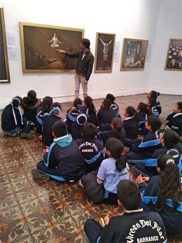 '圖3：當地學校帶學生集體前來觀看畫展，聽學員解說每幅畫的內涵。'