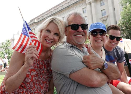 '圖8：來自美國新罕布什爾州的馬克與太太和兩個孩子來華盛頓參加美國獨立日慶祝活動，他們第一次看到法輪功學員的遊行隊伍。'