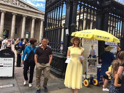 '圖3：尤利婭近日在倫敦大英博物館門外發放法輪大法資料。她還向遊人介紹了法輪功學員遭到的迫害。'