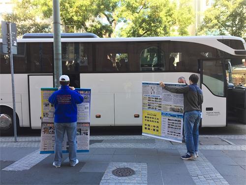 '圖5：中國遊客已上車，兩位法輪功學員舉著真相展板'