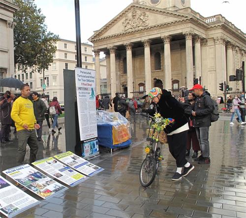 '圖9：二零二零年十月十日，英國威爾士女士簡（Jane）在倫敦特拉法加廣場逐幅認真閱讀法輪功真相展板'