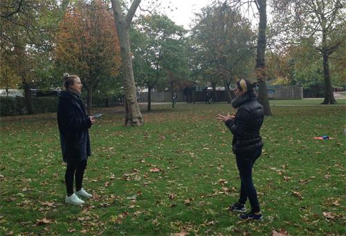 '圖1：二零二零年十月十八日，法輪功學員卡瑞娜（Carina）在倫敦女王公園（Queen's Park）煉功打坐後與不期而遇的瑜珈老師珍妮（Jenny）輕鬆交談'
