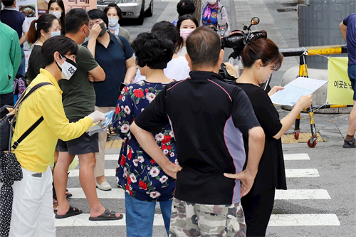 '圖24：法輪功學員在韓國首爾街上派發簡介，讓市民了解真相。'