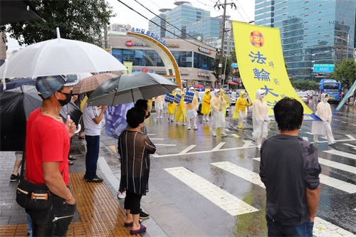 '圖10～11：14：在韓國華人聚居地舉行的聲援3.6億中國人三退大遊行，民眾在聚精會神在觀看遊行。'