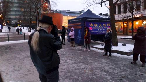 '圖1～2：二零二一年一月九日，芬蘭法輪功學員來到首都赫爾辛基甘比（Kampi）購物中心附近的廣場上，設立真相點。圖為法輪功學員正在演示功法。'