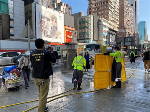 '圖1：二零二一年一月二十九日，香港食環署清潔工用水龍頭、借故清洗街道，欲阻止法輪功學員開設真相點。'