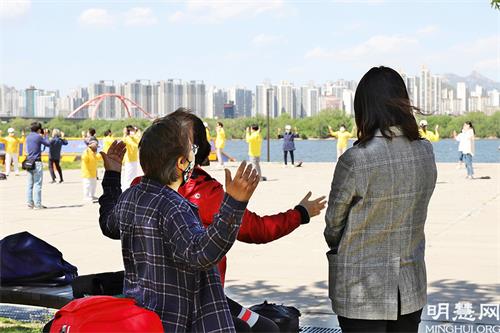 圖20:首爾市民們在觀看汝矣島漢江公園法輪功學員集體煉功，並跟隨學習