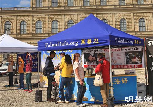 '圖1～2：二零二一年五月二十九日，法輪功學員在慕尼黑馬克西──約瑟夫廣場（Max-Joseph-Platz）舉辦講真相活動，不少民眾駐足了解。'