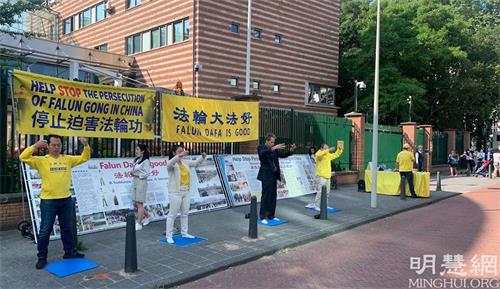 '圖6～7：法輪功學員在中共大使館前面對前來排隊的華人講真相，並集體煉功'