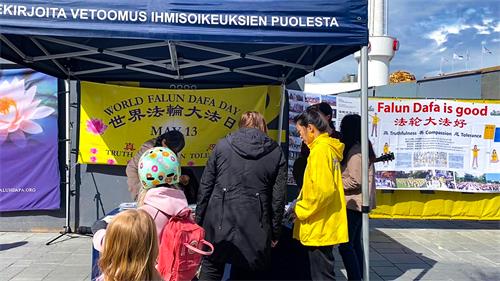 圖2：在赫爾辛基鬧市區，人們駐足「法輪大法日」慶祝活動真相展位