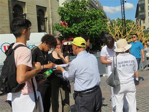 圖2～3：二零二二年六月十一日， 在巴黎市中心的夏特蕾街區，遊人在徵簽表上簽字，支持法輪功學員反迫害。
