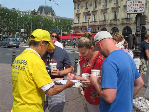 圖5～8：二零二二年六月十九日，在巴黎聖米歇爾廣場（Place Saint-Michel），遊人簽字支持法輪功學員反迫害。