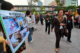 '大陸遊客在台北信義廣場前一零一大樓前觀看法輪功學員舉的真相看板'