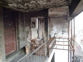 照片左邊木門為完好無損的簡易房，右邊房東簡易房大火的殘壁，鋼架地方是床，木框木門全部燒毀。