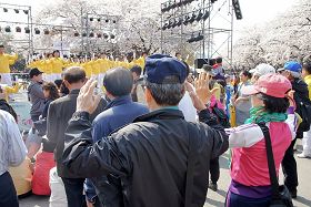 法輪功學員四月十七日週日在櫻花節上做功法演示，觀眾現場學習