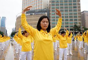 '二零一一年七月十六日，韓國八大市民團體與法輪功學員冒雨在首爾廣場舉行聯合集會，譴責中共對法輪功長達十二年的人權迫害。圖為韓國法輪功學員集體煉功場面。'