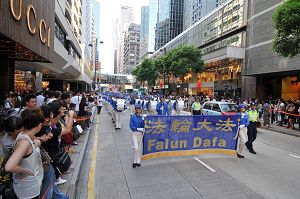 法輪功反迫害遊行隊伍由天國樂團領頭，步入廣東道，馬路兩旁站滿了觀看和拍照的市民及遊客。