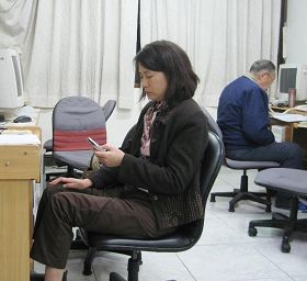 '唐慧如（左）正在給中國大陸民眾撥打電話，八十多歲的老學員（右）正在告訴大陸民眾三退的訊息。'
