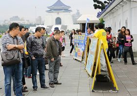'中國大陸遊客駐足在法輪功真相展板前認真觀看。'