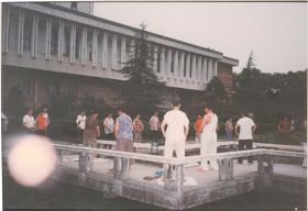 '圖二：一九九八年七月二十九日清晨，拍攝於湖南大學圖書館旁的法輪功煉功點，學員們正在煉第二套功法的「腹前抱輪」動作。照片中左下方，照相機拍到一個大光球（法輪）'