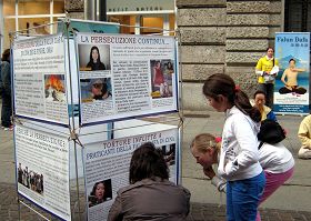 一位意大利母親蹲在展板前，向她的孩子解釋在圖片上的迫害真相
