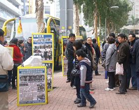 '許多中國大陸遊客在嘉樂軒飯店前觀看法輪功真相展板'