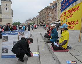 古城廣場上遊客在反對中共迫害法輪功的徵簽簿上簽名