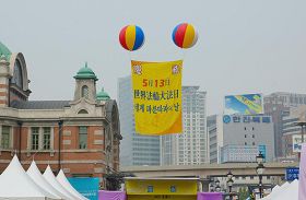 '活動現場首爾站上空飄揚著「慶祝法輪大法洪傳21週年」的大型氣球'