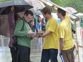 '遊客在雨中簽名反對中共活摘法輪功學員器官'
