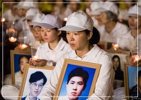 圖9：法輪功學員手捧著被迫害致死的中國法輪功學員照片，表情靜穆。