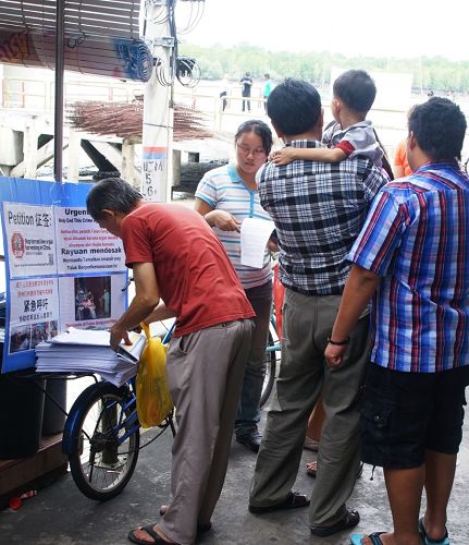 法輪功學員在馬國吉膽島村口的講真相徵簽行動引起民眾的關注