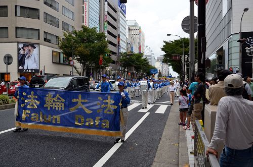 「反對中共活摘法輪功學員器官」的遊行隊伍由天國樂團做前導，在名古屋市最繁華地段──榮（Sakae）進行，許多民眾駐足觀看。