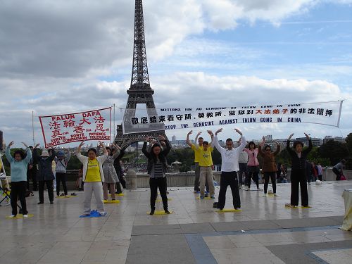 圖1：法輪功學員在巴黎埃菲爾鐵塔前傳播法輪功的真相。圖為法輪功學員正在演示第二套功法。