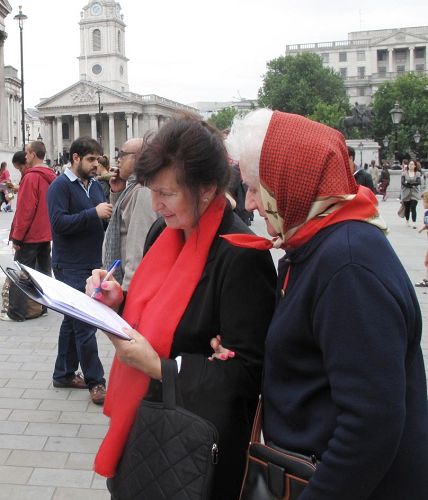 '兩位移居倫敦的波蘭女士互相鼓勵在反迫害徵簽表上簽名'