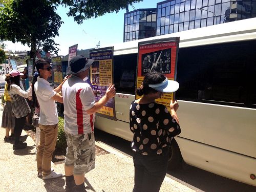 法輪功學員向遊覽車上的中國遊客展示真相展板