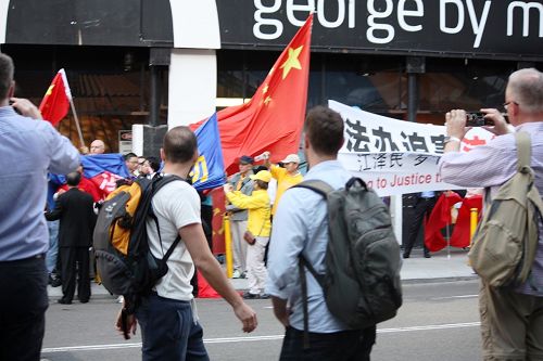 在悉尼主街喬治街上，親共暴徒搶奪法輪功橫幅。路過的澳洲民眾紛紛拍照，並譴責暴徒的行徑。