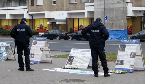 圖6：華沙中使館門前，執勤警察觀看法輪功真相展板