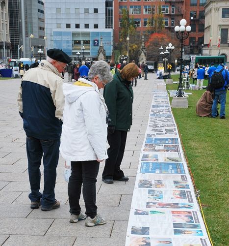 加拿大國會山前，路人閱讀法輪功真相圖片