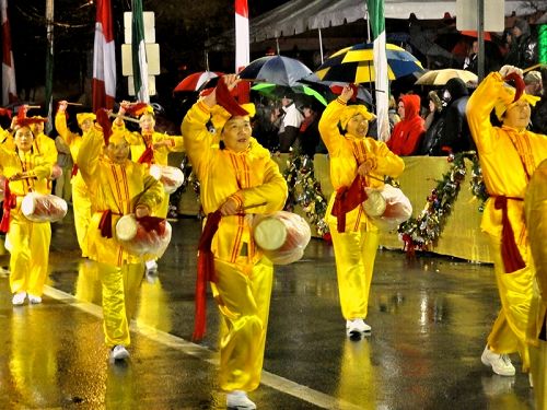 法輪功腰鼓隊在夾道民眾的熱情歡迎中冒雨行進
