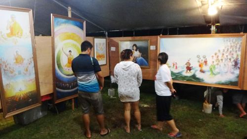 第三十三屆塞班島火樹節，遊客觀賞「真善忍國際美展」畫作