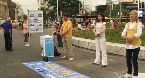 學員們在首都貝爾格萊德共和廣場演示功法，民眾看真相展板