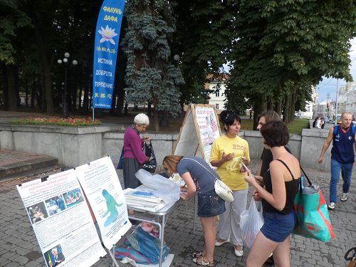 圖7：在哈爾科夫市的真相點，人們經過時看到揭露中共酷刑折磨法輪功學員的圖片，紛紛駐足了解真相。明白真相後，人們立即在「反對中共強摘法輪功學員器官」的徵簽表上簽名。