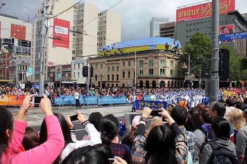 很多華人觀眾在夾道旁向正在走來的法輪功天國樂團拍照