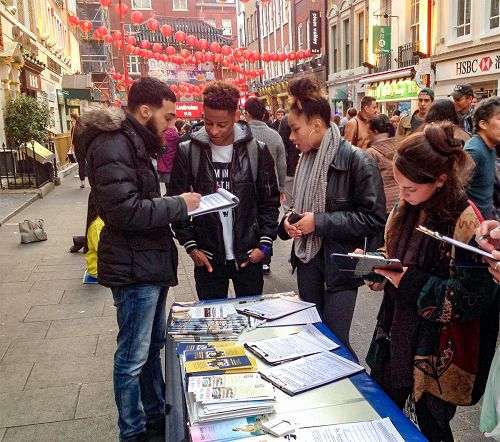 圖12：二零一五年十月三日，法輪功學員在倫敦唐人街舉行講真相反迫害活動，許多民眾簽名支持，其中右一是 SOAS的一位學生。