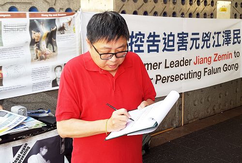 圖1：帕拉馬塔市議員約翰﹒胡正在簽名聲援中國法輪功學員控告迫害法輪功元凶江澤民