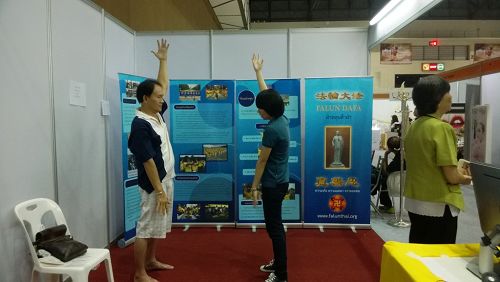 泰國健康與美容展上，參觀者向法輪功學員學煉功法