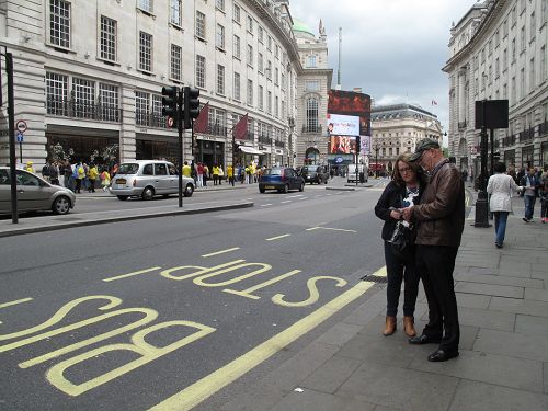 圖8：從諾丁漢郡來倫敦探親的湯姆普森和芭芭拉夫婦在皮卡迪利大街上看到法輪功遊行隊伍，接過真相傳單認真閱讀起來